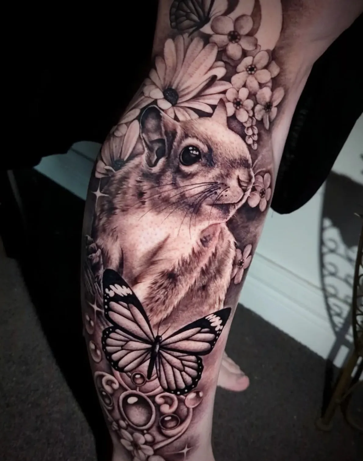 Realistic rabbit portrait tattoo surrounded by delicate floral elements